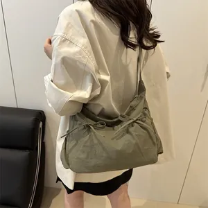 Close-up of olive green messenger bag featuring pleated nylon and bow details