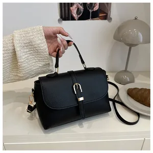 Detail shot of the elegant black pebble leather handbag with gold buckle decoration