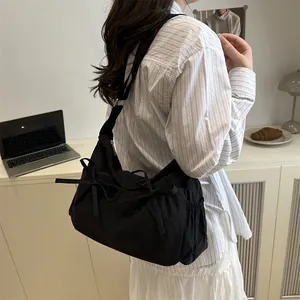 Detail of black crossbody bag with bow decorations and side drawstring pocket on model