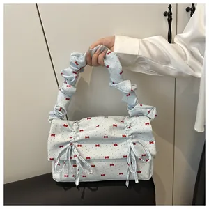 Detail of light blue pleated handbag with red bows and ruffles shown in a lifestyle setting
