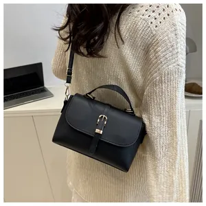 Close-up of black litchi pattern leather bag with golden buckle and textured finish