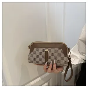 Detail of the brown checkered handle bag with a zipper and detachable wrist strap