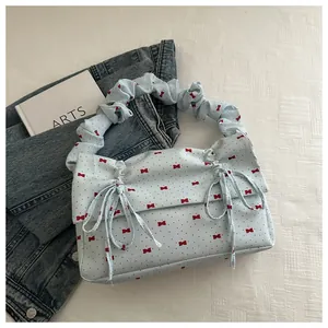 Detail of light blue ruffled handbag featuring red bow patterns and drawstring ribbons