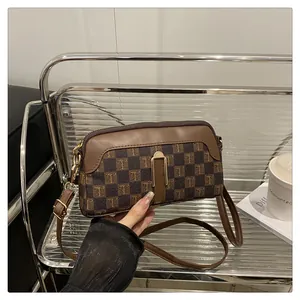Detail view of brown checkerboard handbag with T-pattern and golden metal buckle clasp