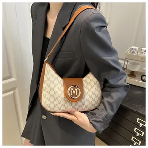 Detail of vintage beige canvas underarm bag with M-logo print and leather trim buckle