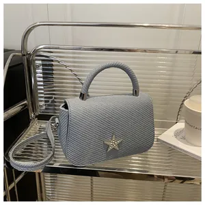 Detail of light blue woven texture handbag with a sparkling rhinestone star ornament
