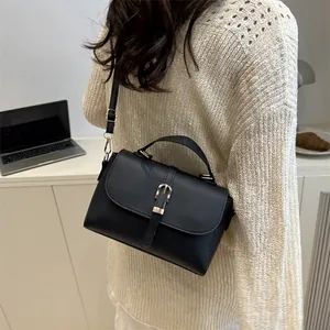 Classic black lychee pattern crossbody bag with gold buckle on a stylish office desk