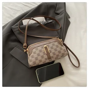Detail of monogram canvas crossbody bag with brown leather trim and golden metal clasp