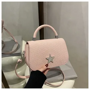 Detailed view of the pink crossbody bag featuring a star clasp and twill texture