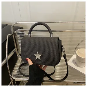 Close-up of black woven handbag with a silver star rhinestone and metallic hardware