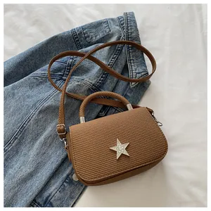 Detail of a brown woven handbag with a sparkling rhinestone star emblem and strap