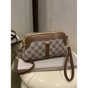 Retro checkered crossbody bag with tan leather trim and gold hardware on book stand