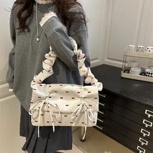 White canvas shoulder bag with red bow prints and stylish pleated cloud strap detail