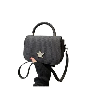 Black textured tote bag with silver star emblem and detachable shoulder strap