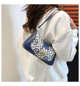 Detail der blauen Monogramm-Schultertasche mit goldenem M-Verschluss und Lederriemen