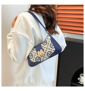 Detail der Vintage-Schultertasche mit goldenem M-Verschluss und dunkelblauer Paspel