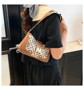 Detail der Vintage-Schultertasche mit goldener M-Schnalle und braunem Lederbesatz