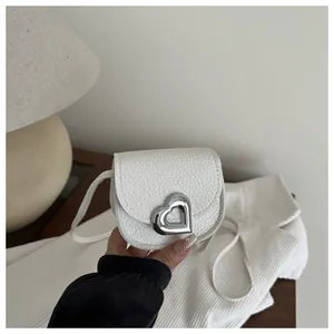 Mini white heart saddle bag for girls featuring silver metal buckle and lychee leather