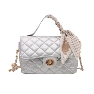 Silver quilted crossbody bag with silk scarf handle and golden chain strap on white background