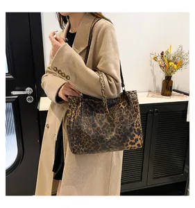 Detail view of a large leopard print tote bag with black straps and spacious interior