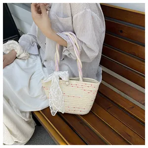 Detail of handmade straw tote with large lace bow and colorful stitching texture