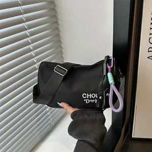 Minimalist black nylon pillow bag with heart embroidery and a purple braided charm