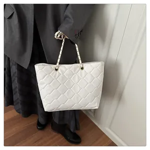 Close-up of white diamond quilted tote bag with gold chain and leather woven handle