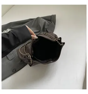 Detail view of large brown pleated chain bag showing interior compartment and zipper pocket