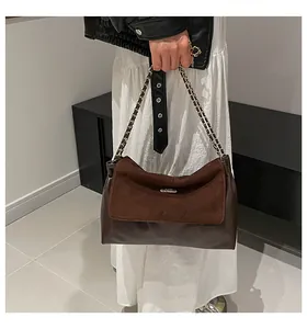 Detail of a luxury brown shoulder bag with suede flap and gold metal chain strap