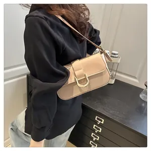 Detail of a beige patent leather shoulder bag with a gold horseshoe buckle and strap