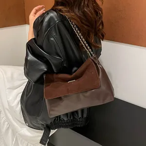 Chic dark brown chain shoulder bag with suede patchwork design on a female model