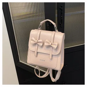Detail of light pink PU leather backpack featuring 3D butterfly bows and silver lettering