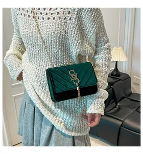 Détail du sac à bandoulière en velours avec matelassage en V et pompon doré élégant