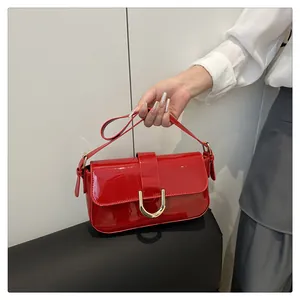 Close-up of bright red patent leather handbag with golden horseshoe buckle detail