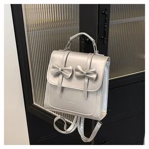 Detail of silver metallic mini backpack with bow accents and top handle design