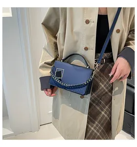 Detail of dark blue leather handbag with gold hardware and woven chain strap for women
