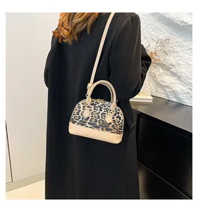 Detailed side view of leopard print shell bag with beige leather trim on black blazer