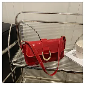 Close-up of shiny red patent leather shoulder bag with golden U-shaped buckle detail