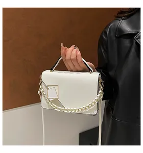 Close-up of a white rectangular bag with gold buckle detail and chain strap