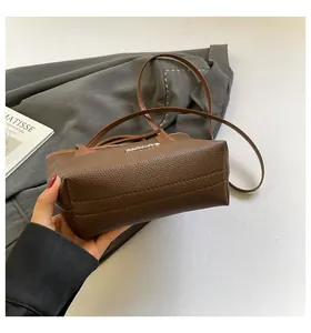 Detail of dark brown pebble leather shoulder bag with sleek handles and adjustable strap