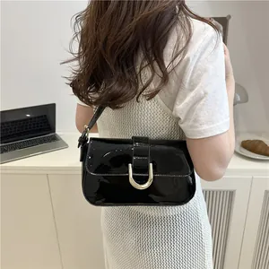 Black patent leather shoulder bag with silver horseshoe buckle shown on a model