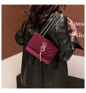 Détail du sac à bandoulière en velours bordeaux vintage avec matelassage en V et pompon doré