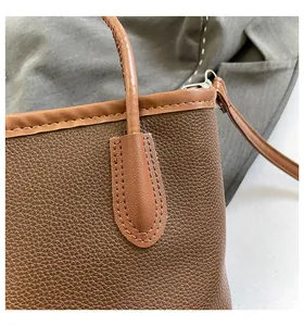 Close-up of brown pebbled leather texture and stitching on a minimalist bucket bag