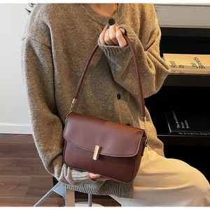 Detailed side view of a brown leather crossbody bag with a gold metal clasp on a model