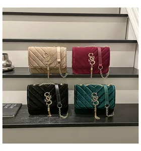 Détail de quatre sacs bandoulière en velours de couleurs variées avec matelassage en V et pompons