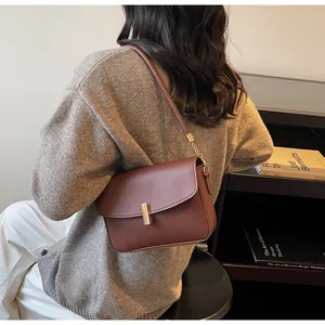 Close-up of retro brown shoulder bag with gold metal bar clasp worn on shoulder