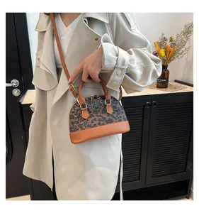 Chic leopard print shell bag with brown faux leather trim and gold hardware details