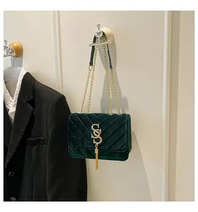 Détail du sac à bandoulière en velours vert foncé avec motif en V et chaîne dorée