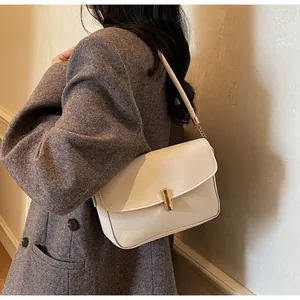 Detail of ivory flap crossbody bag with gold buckle on a model in tweed suit