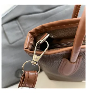 Macro shot of brown pebble leather bucket bag side with silver metal hardware and stitching